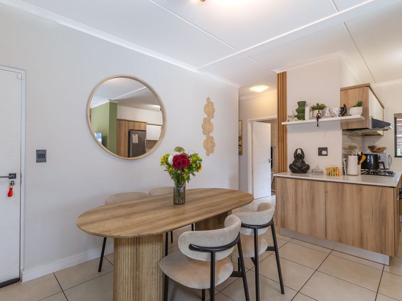 An open-plan living and dining area featuring modern wood-finish kitchen cabinetry, tiled flooring, and a functional layout with integrated kitchen appliances.