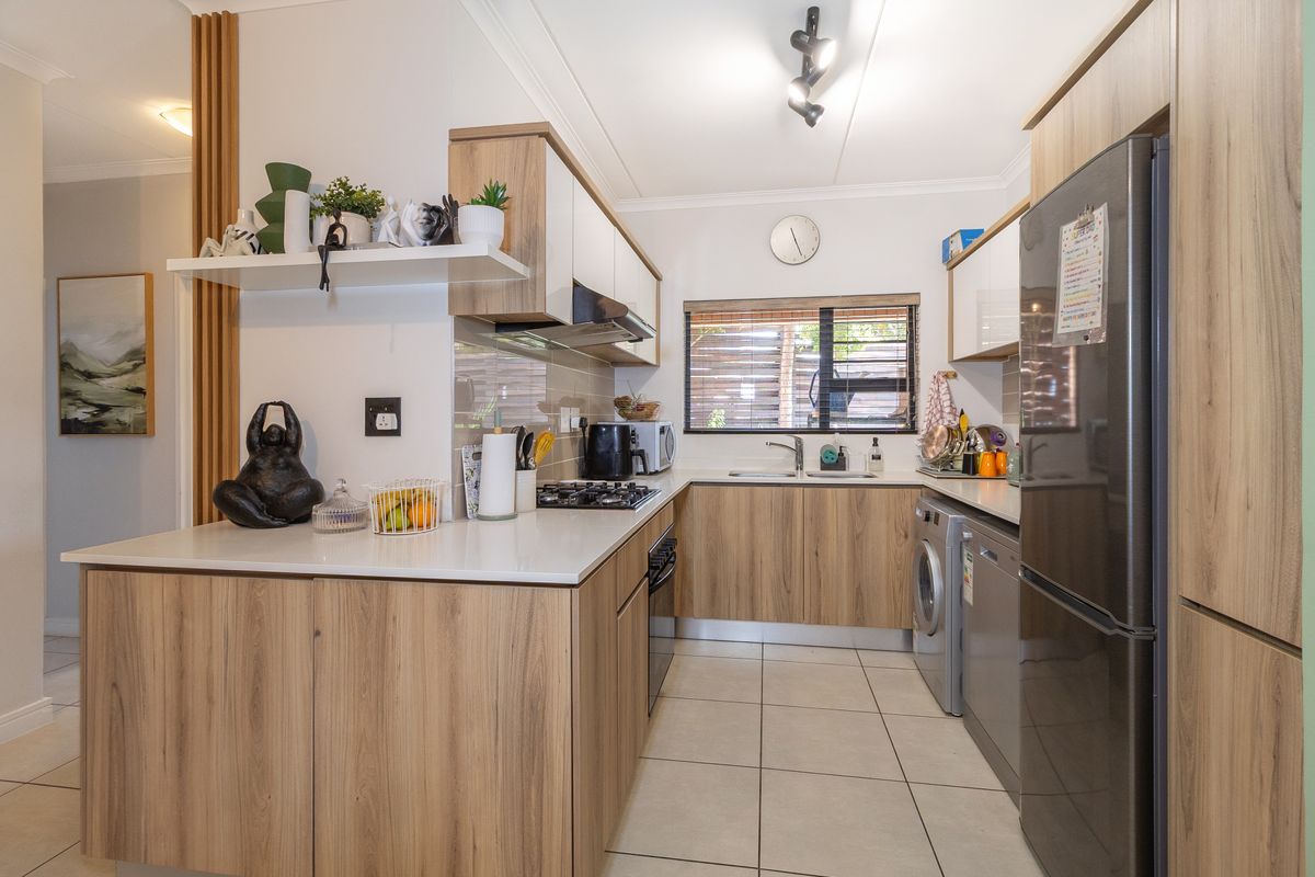 Modern kitchen featuring wood-grain cabinetry, stone countertops, gas hob, integrated appliances, and tiled flooring, offering a functional and well-maintained workspace.
