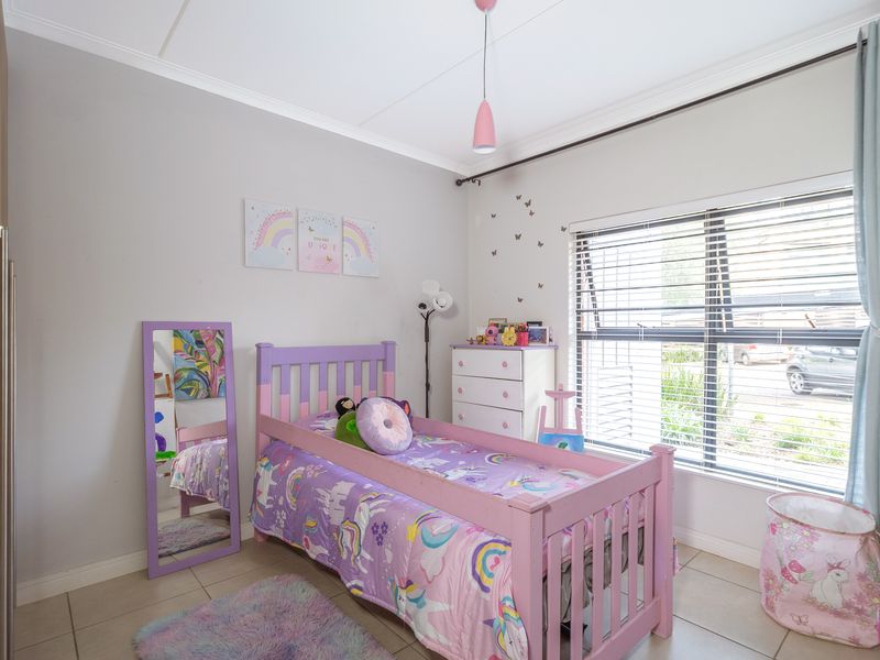 A well-maintained bedroom featuring tiled flooring, built-in wardrobe storage, and large windows with venetian blinds for natural light.
