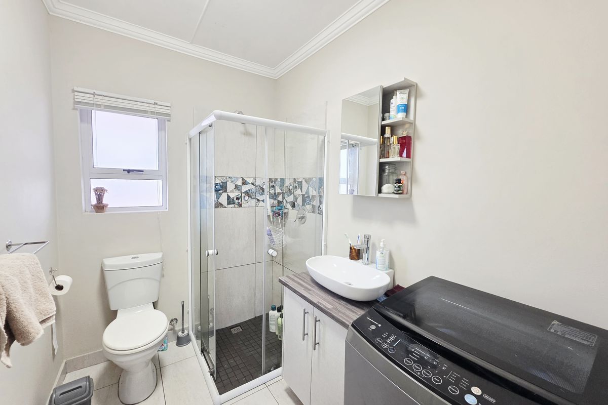 A functional bathroom featuring a glass-enclosed shower, a modern vessel sink on a vanity cabinet, and a standard toilet.