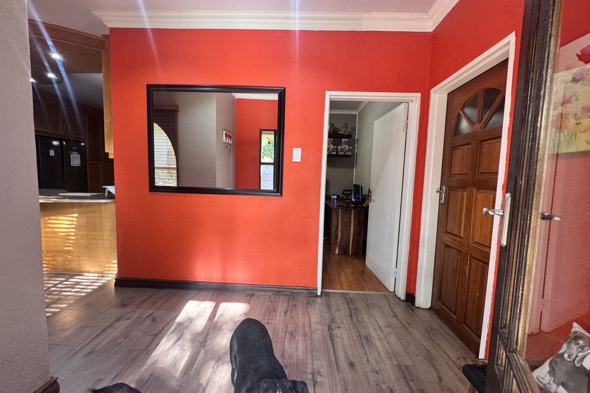 A bright living area featuring laminate flooring, coving, and a solid timber entrance door, providing a neutral base for interior design updates.