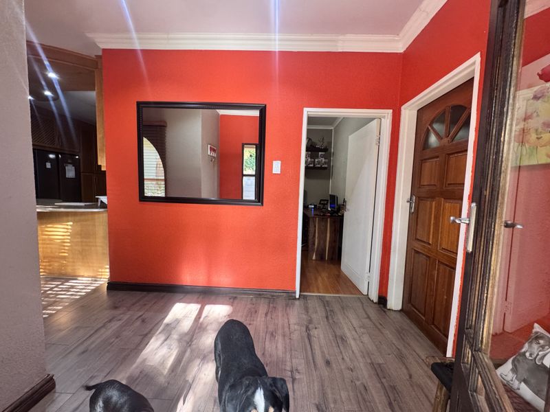 A bright living area featuring laminate flooring, coving, and a solid timber entrance door, providing a neutral base for interior design updates.
