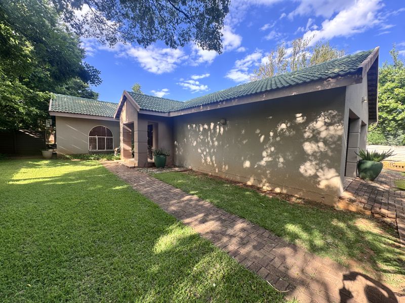 Front exterior view of the house featuring a green tiled roof, stucco facade, and a brick paved walkway leading to the entrance.