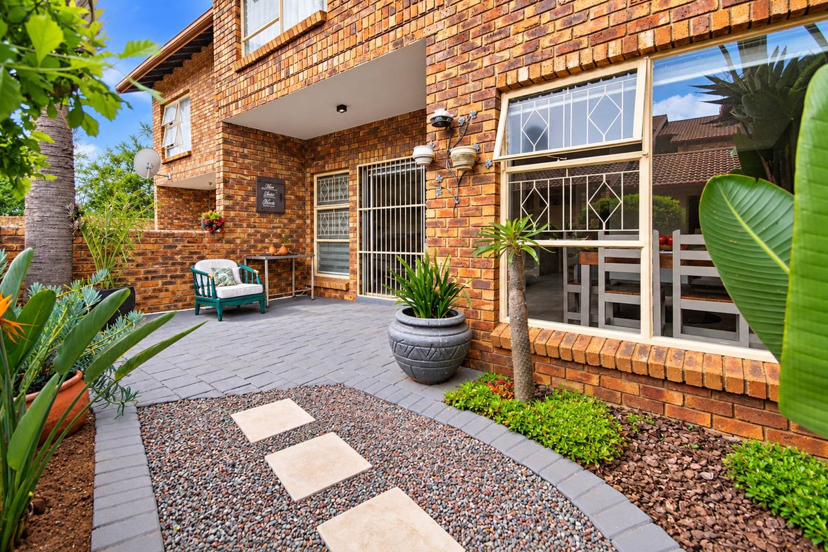 A well-maintained rear patio area featuring face brick construction, paved flooring, and a landscaped garden path with stepping stones.
