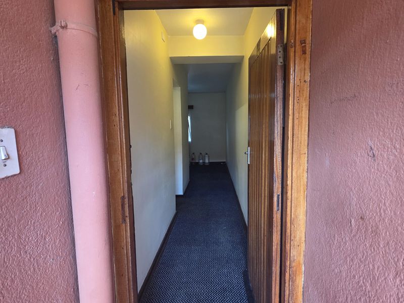 View of the property entrance featuring a wooden door frame, carpeted hallway, and exterior wall with a visible downpipe.