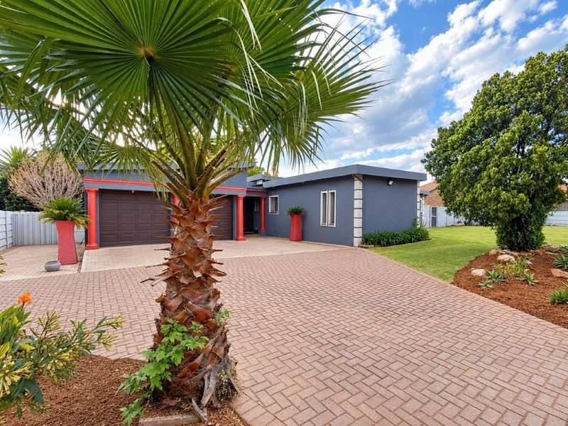 Front view of a well-maintained house featuring a paved driveway, double garage, and landscaped garden area.