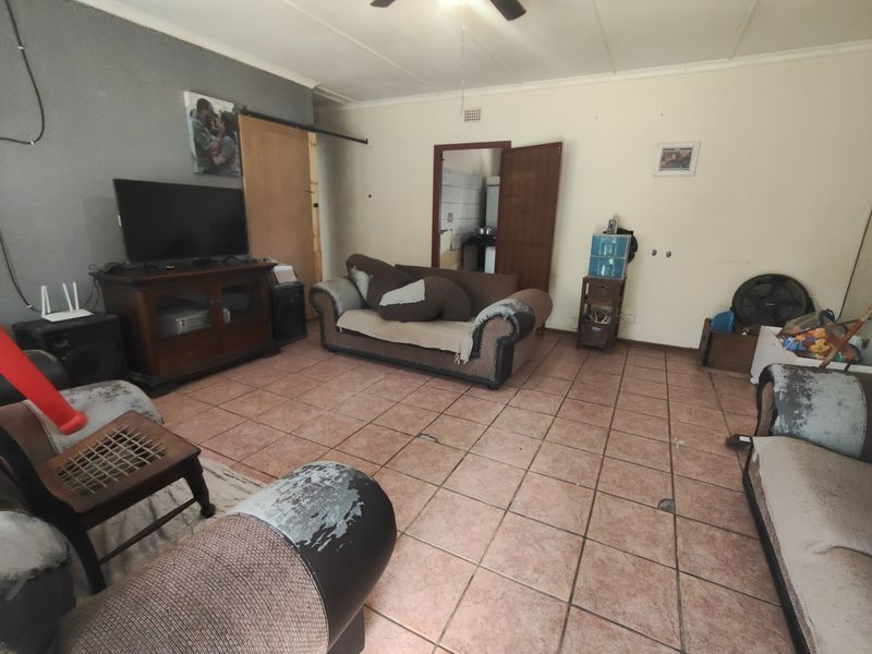 A living room featuring tiled flooring and a ceiling fan, offering a functional space with potential for cosmetic updates and modernization.