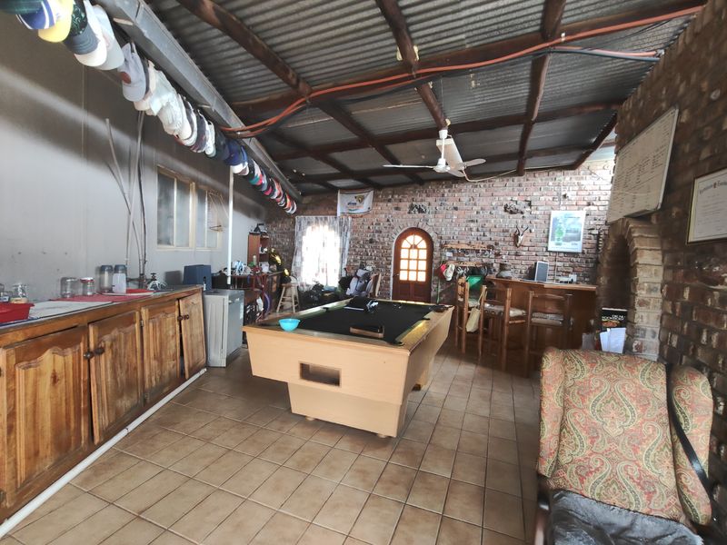 Rustic entertainment area featuring a built-in bar, exposed brick walls, and timber roof structure, offering a casual space for social gatherings.