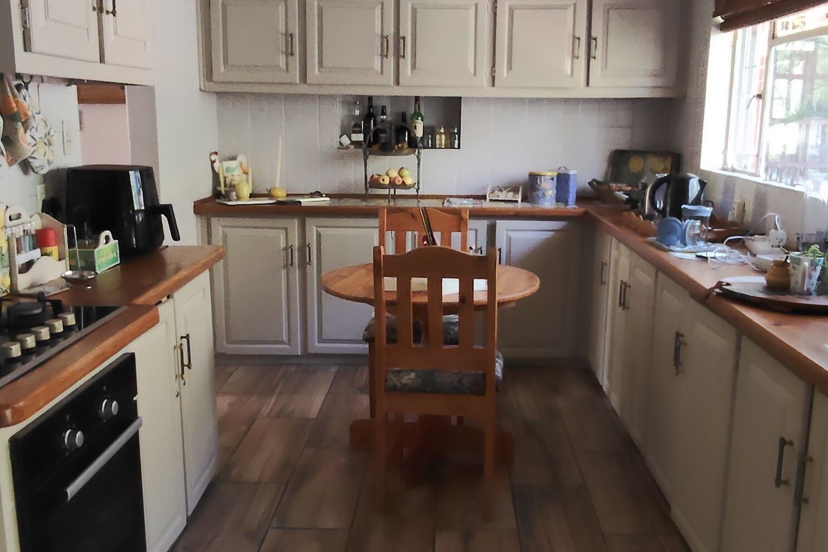 A functional kitchen featuring wooden countertops, built-in cabinetry, an integrated oven, and tiled flooring, offering a practical layout with potential for cosmetic updates.