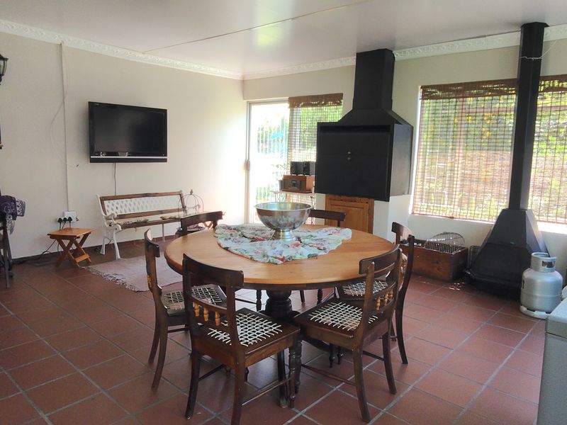 Spacious covered patio featuring tiled flooring, a built-in braai, and a fireplace, offering a versatile outdoor entertainment area.