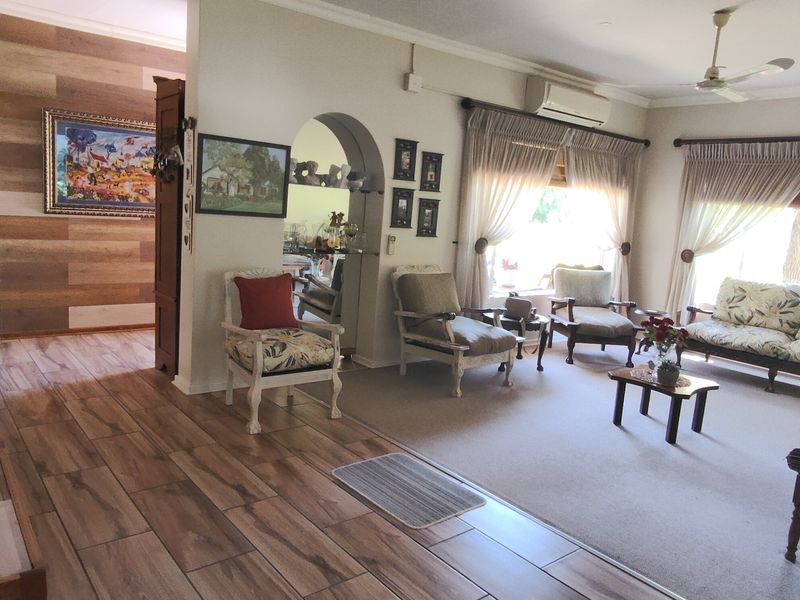 Spacious living room featuring a mix of wood-look tile and carpeted flooring, an arched entryway, and wall-mounted air conditioning.
