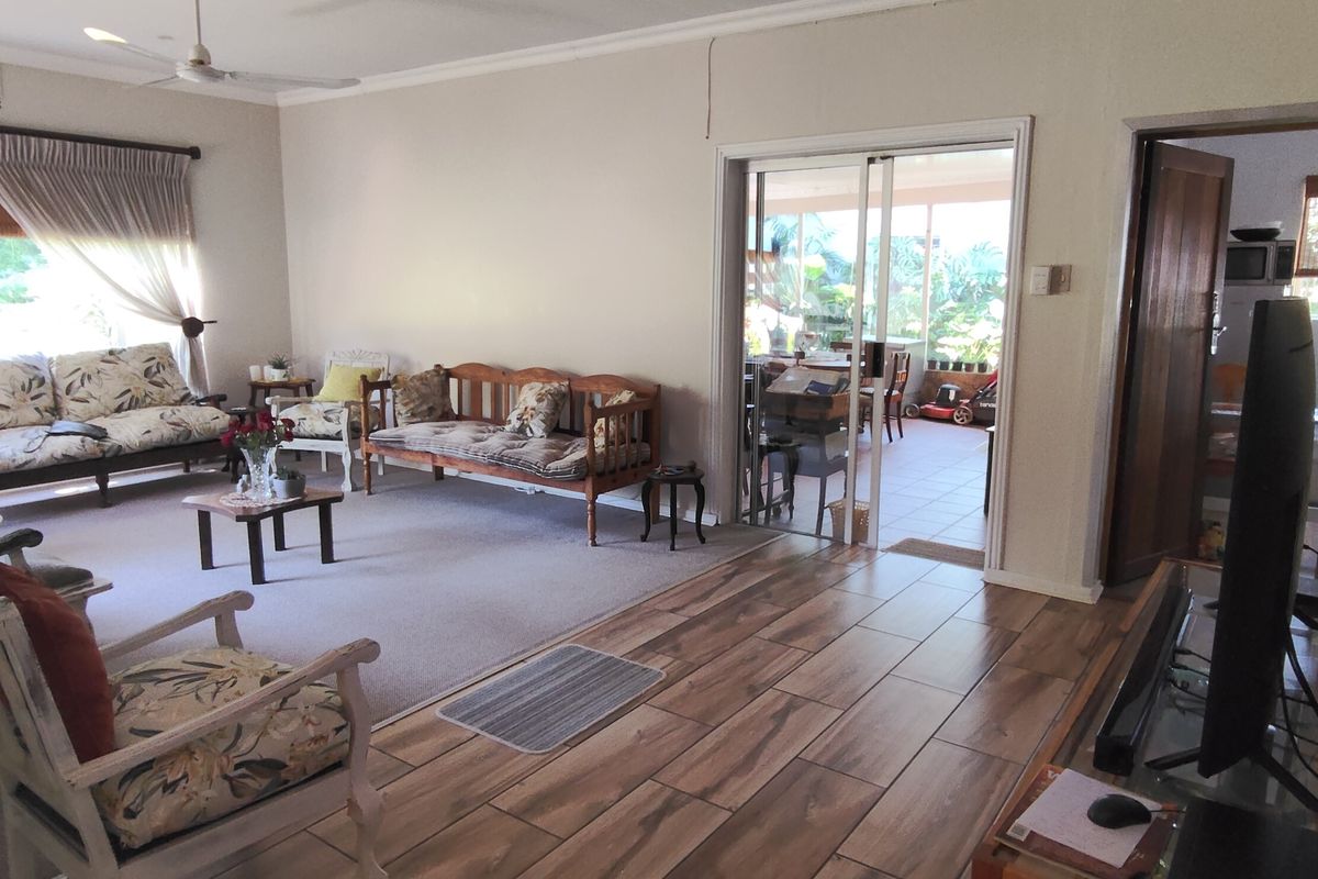 Spacious living room featuring a mix of carpet and wood-look tile flooring, ceiling fan, and sliding glass doors leading to an outdoor patio area.