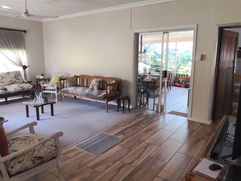 Spacious living room featuring a mix of carpet and wood-look tile flooring, ceiling fan, and sliding glass doors leading to an outdoor patio area.