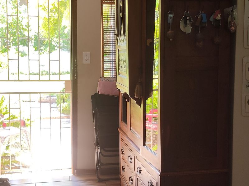 An inviting entrance hall featuring modern wood-look tiled flooring, recessed ceiling lighting, and a secure exterior door with a metal security gate.