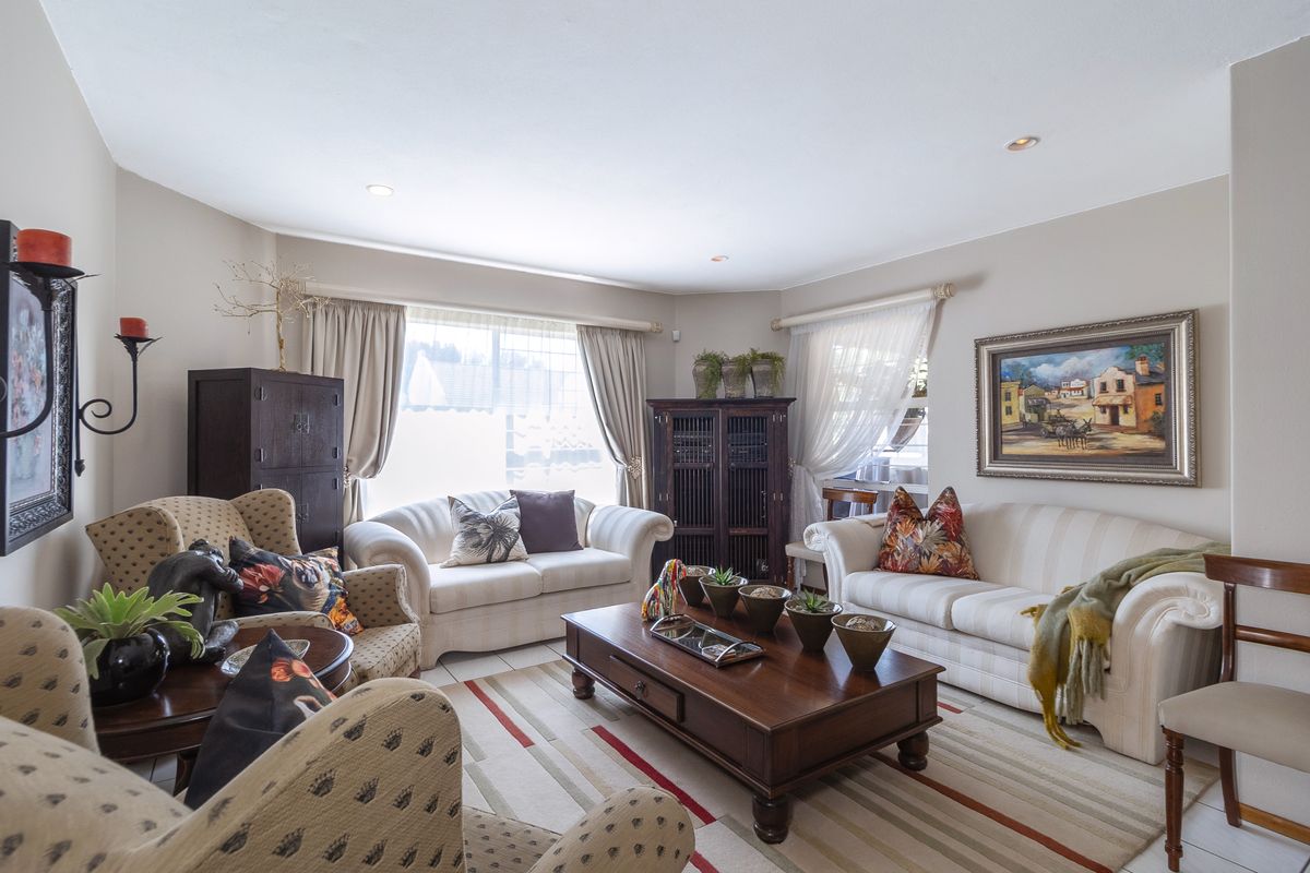 A well-maintained living room featuring neutral wall tones, recessed downlighting, and tiled flooring, creating a comfortable and inviting space.