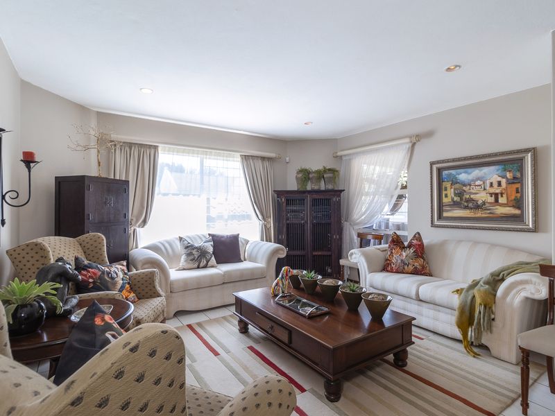 A well-maintained living room featuring neutral wall tones, recessed downlighting, and tiled flooring, creating a comfortable and inviting space.