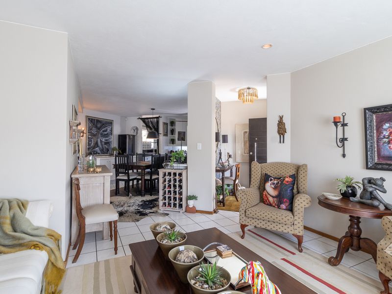 Spacious open-plan living and dining area featuring ceramic tile flooring, recessed lighting, and a convenient built-in wine storage unit.