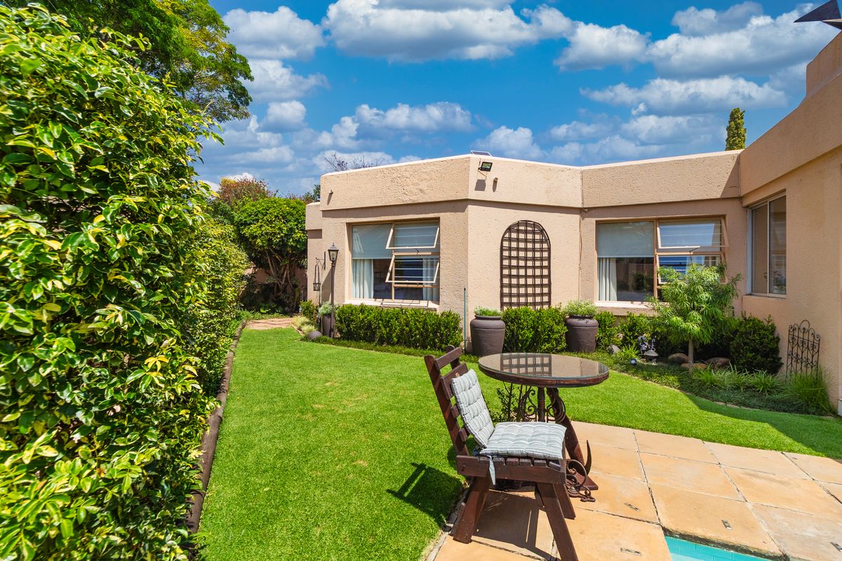 A well-maintained rear garden featuring a tiled patio area, swimming pool, and established landscaping adjacent to the house exterior.