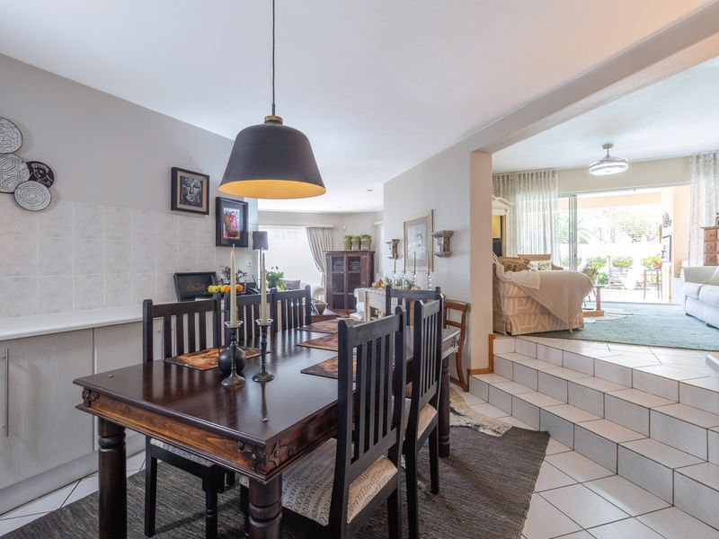 Open plan dining area featuring tiled flooring, built-in cabinetry, and a stepped transition leading to a bright living space with sliding glass door access.