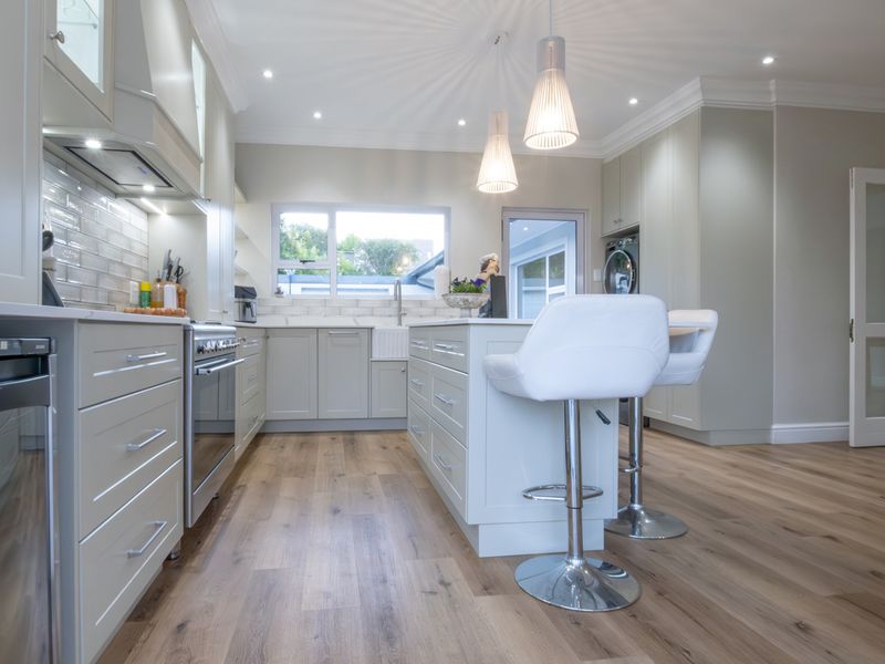 Modern kitchen featuring a central island, shaker-style cabinetry, farmhouse sink, subway tile backsplash, and high-quality finishes throughout.