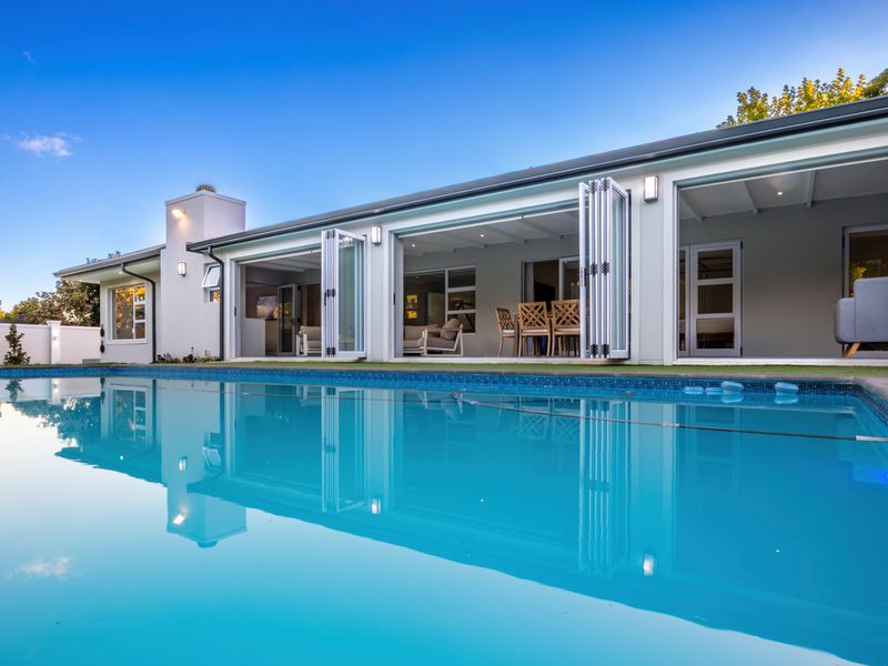 A well-maintained swimming pool area featuring modern bi-fold doors that open directly into the home, creating a seamless indoor-outdoor living space.