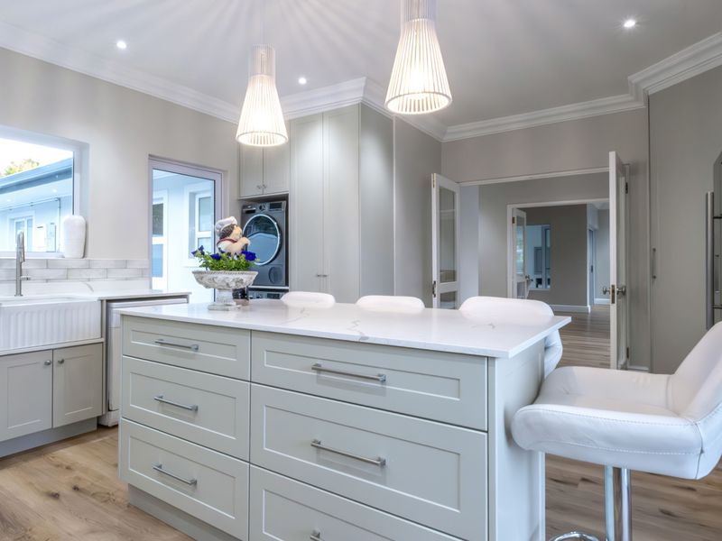 Modern kitchen featuring a central island with quartz countertops, farmhouse sink, shaker cabinetry, and high-quality finishes throughout.