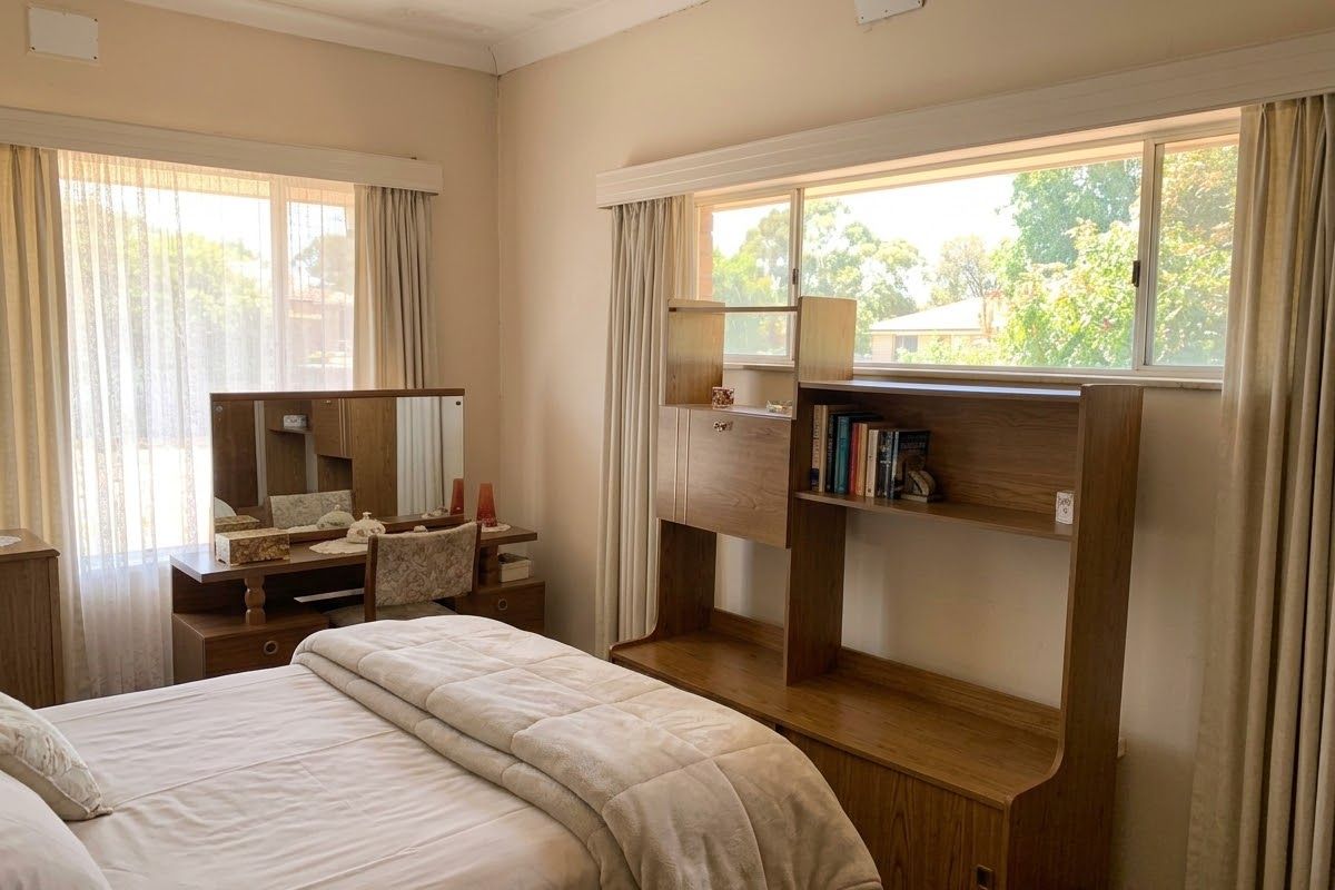 A bedroom featuring large windows with natural light, requiring some cosmetic attention to the ceiling and paintwork.