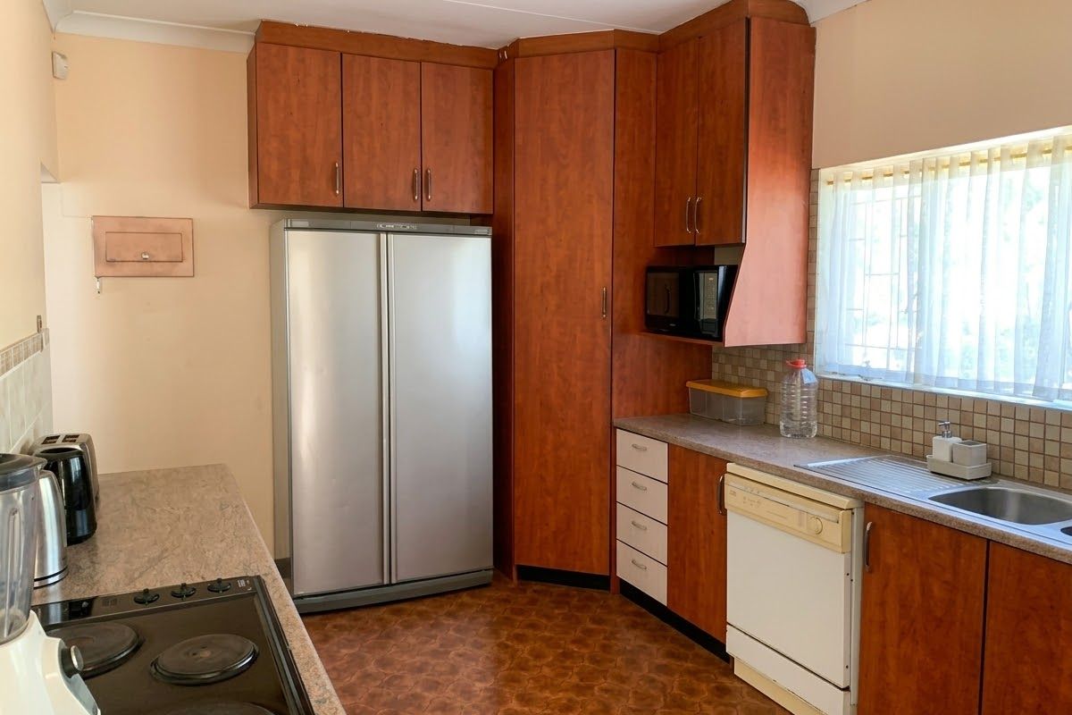 Functional kitchen featuring wood-tone cabinetry, laminate countertops, tiled backsplash, and integrated appliances, offering a practical layout with potential for modern updates.