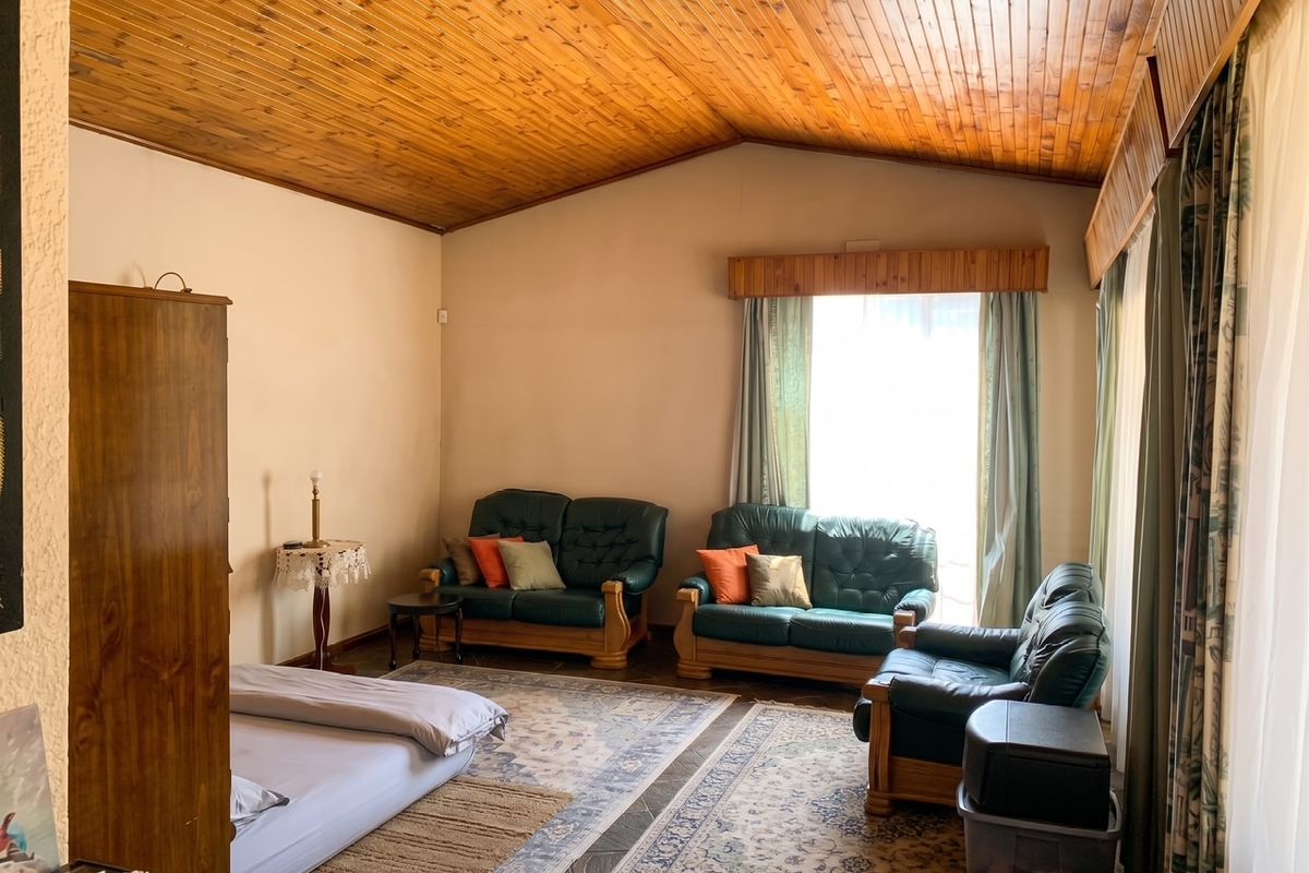Spacious living room featuring a high vaulted timber ceiling, tiled flooring, and large windows with timber pelmets, offering a warm and traditional aesthetic.