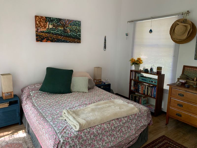 A cozy bedroom featuring laminate flooring and venetian blinds, offering a comfortable and functional living space.