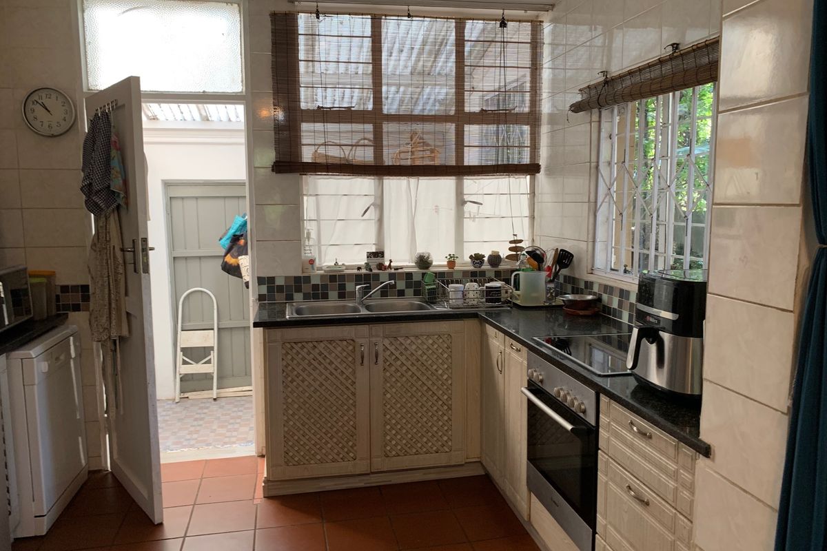 Functional kitchen featuring built-in cabinetry, double sink, integrated oven and hob, tiled splashbacks, and direct access to an outdoor utility area.
