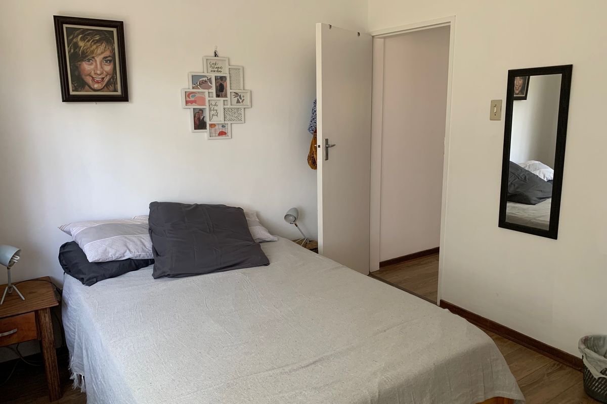 A functional bedroom featuring laminate flooring and neutral wall finishes, providing a comfortable and well-lit sleeping space.