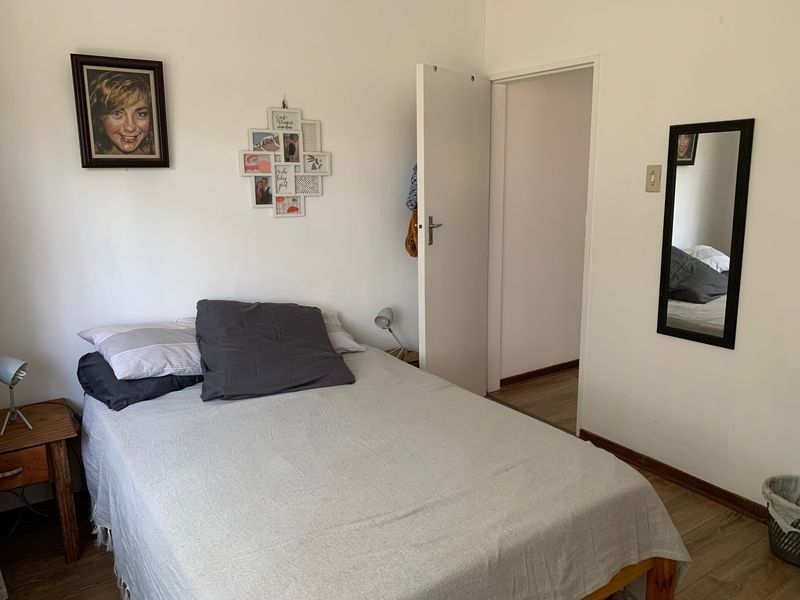 A functional bedroom featuring laminate flooring and neutral wall finishes, providing a comfortable and well-lit sleeping space.