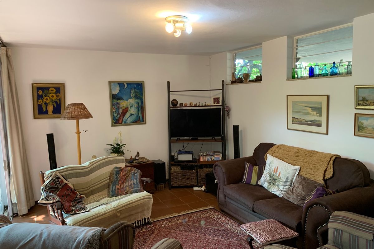 A comfortable living room featuring terracotta floor tiles and high-level clerestory windows, providing a functional and lived-in space.