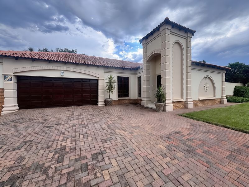 Front elevation of a townhouse featuring a paved driveway, double garage, and distinctive arched entrance tower with terracotta roof tiles.