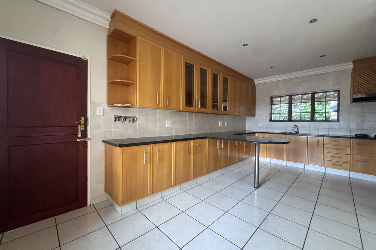 Spacious kitchen featuring extensive wooden cabinetry, granite countertops, a breakfast bar, and tiled flooring, offering a functional layout for culinary activities.
