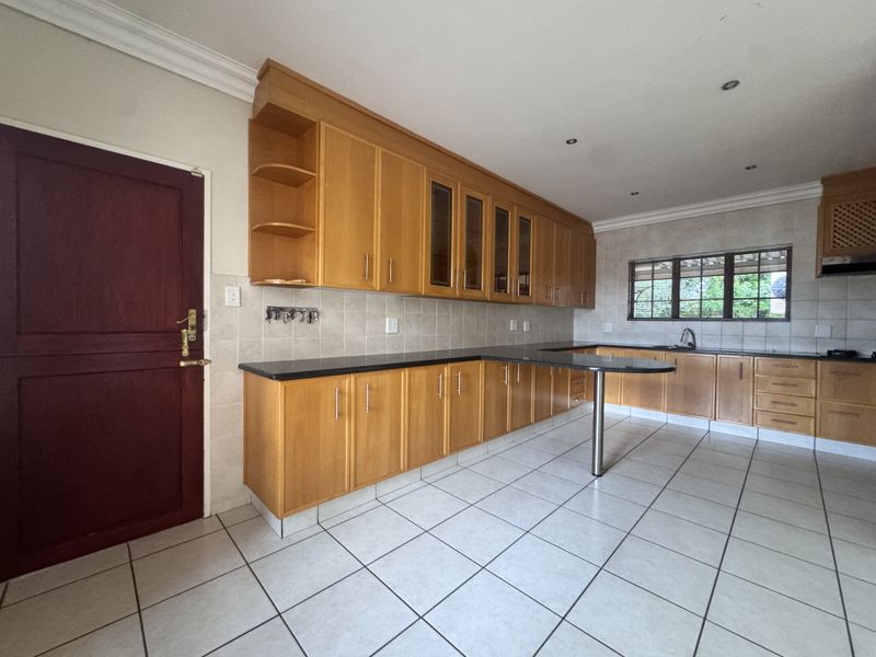 Spacious kitchen featuring extensive wooden cabinetry, granite countertops, a breakfast bar, and tiled flooring, offering a functional layout for culinary activities.