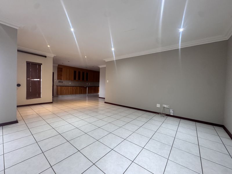 Spacious open-plan living and kitchen area featuring neutral walls, tiled flooring, recessed lighting, and wooden cabinetry, offering a versatile blank canvas for interior design.