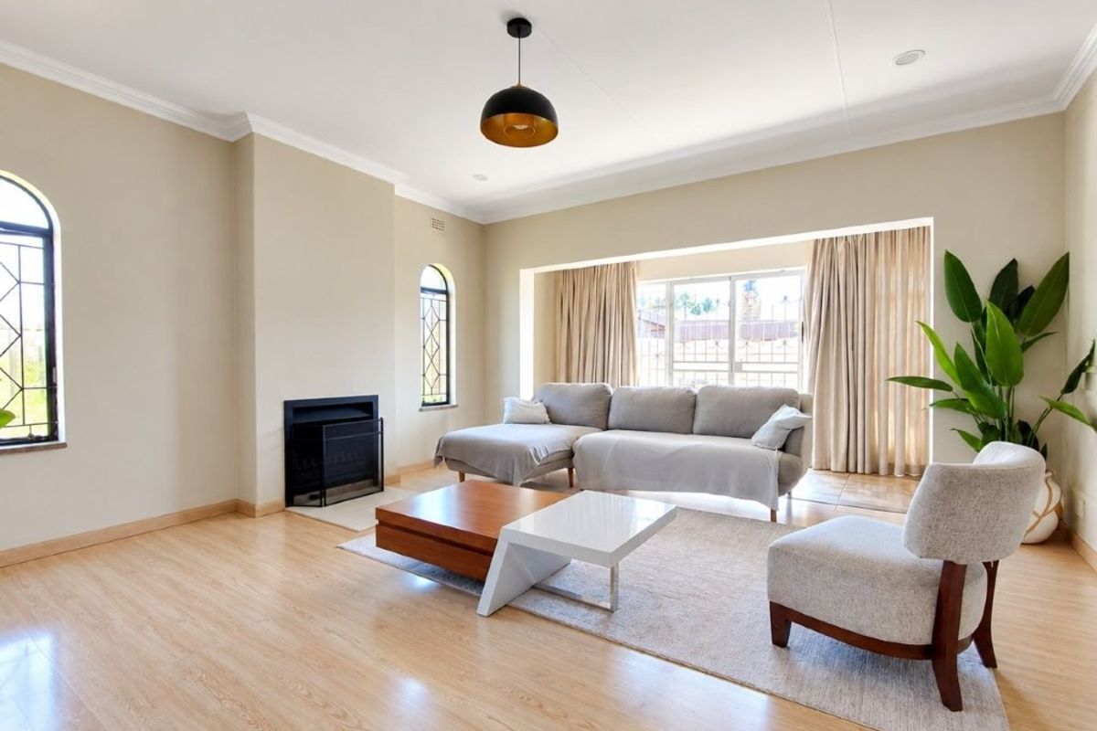 Spacious living room featuring light laminate flooring, a built-in fireplace, and large windows that provide ample natural light.