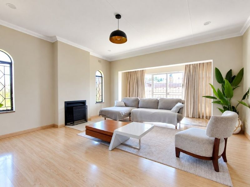 Spacious living room featuring light laminate flooring, a built-in fireplace, and large windows that provide ample natural light.