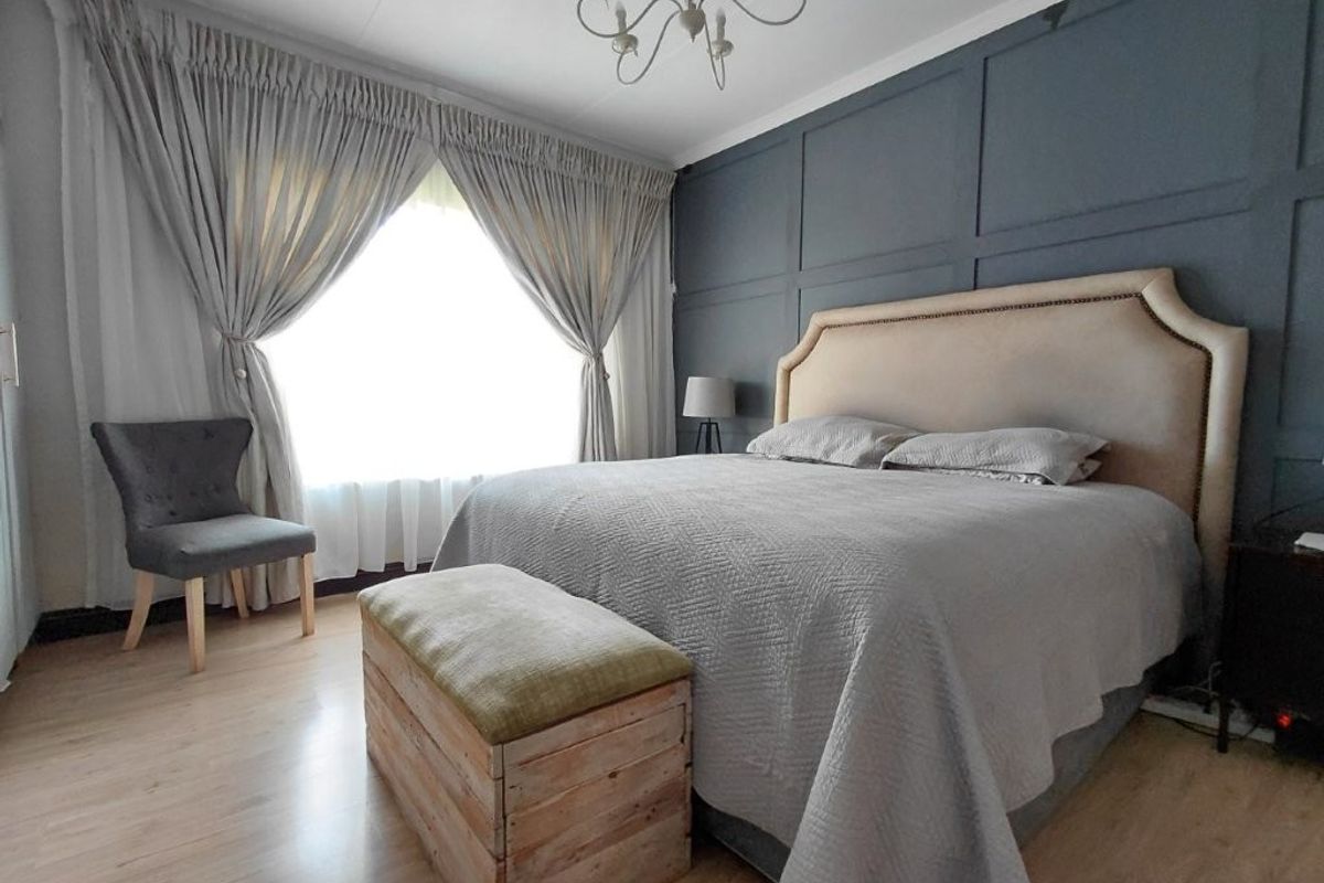 A well-presented bedroom featuring light laminate flooring and a dark grey feature wall with decorative paneling.