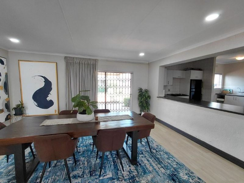 Open plan dining area featuring laminate flooring, recessed lighting, and a breakfast bar overlooking the kitchen, with direct access to the outdoor area.