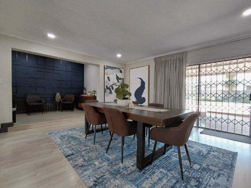 Spacious dining area featuring modern decorative wall paneling, recessed lighting, and large sliding glass doors with security gates leading to the exterior.