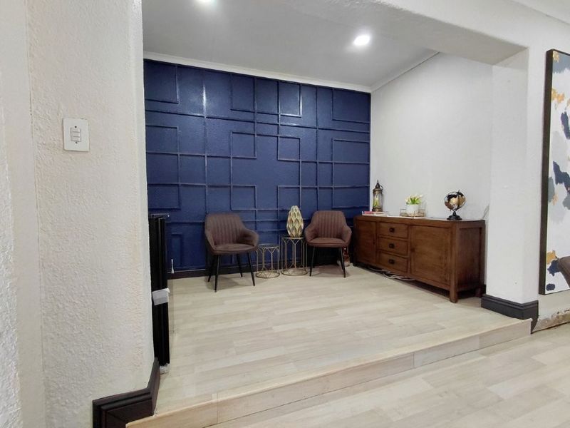 Living area featuring a decorative blue wainscoting feature wall, raised platform, and light-toned laminate flooring.