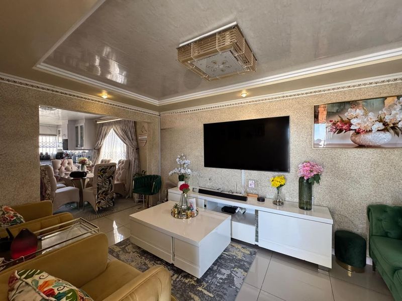Spacious open-plan living area featuring decorative ceiling details, textured wall finishes, and tiled flooring, seamlessly connecting to the adjacent dining space.