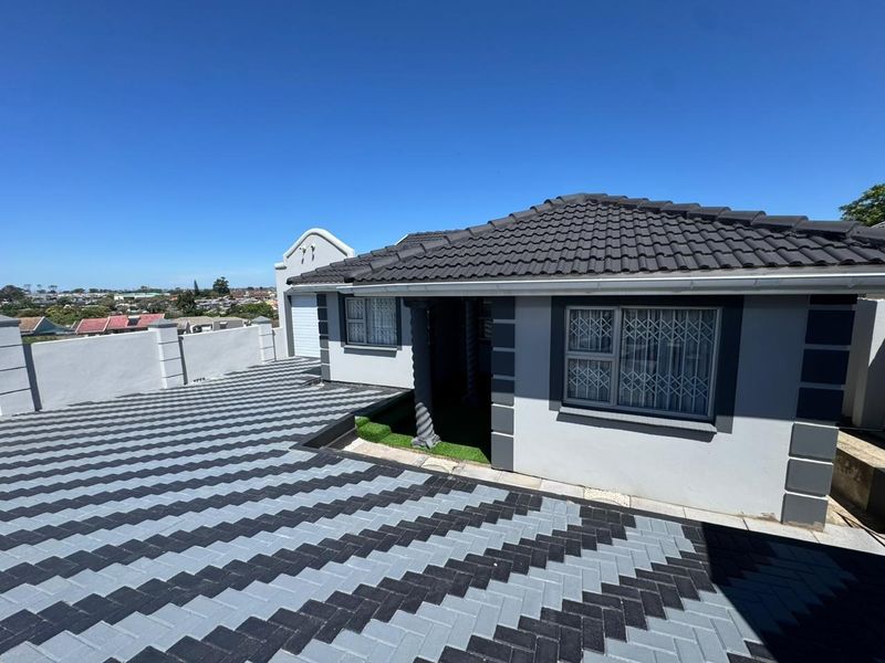 Front exterior view of a well-maintained house featuring a modern paved driveway, tiled roof, and secure window bars.