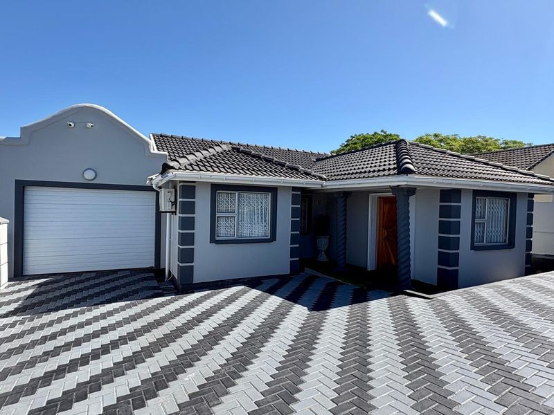 Well-maintained front elevation featuring a modern paved driveway, tiled roof, and secure garage access with decorative architectural columns.