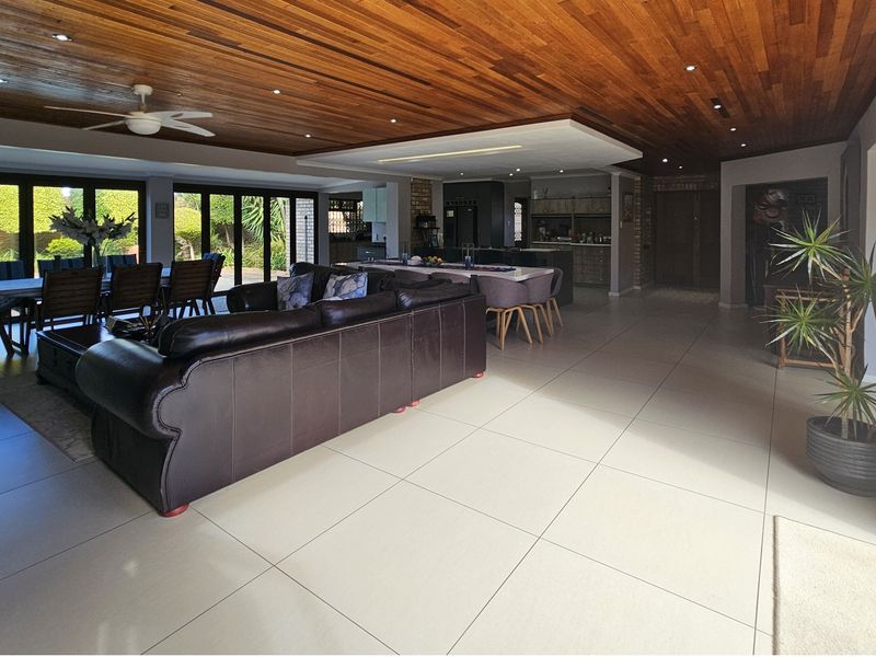 Spacious open-plan living and dining area featuring a warm timber-clad ceiling, large format floor tiles, and seamless access to the outdoor patio through stacking doors.