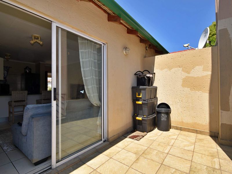 A compact outdoor patio area featuring tiled flooring and a sliding glass door providing access to the interior living space.