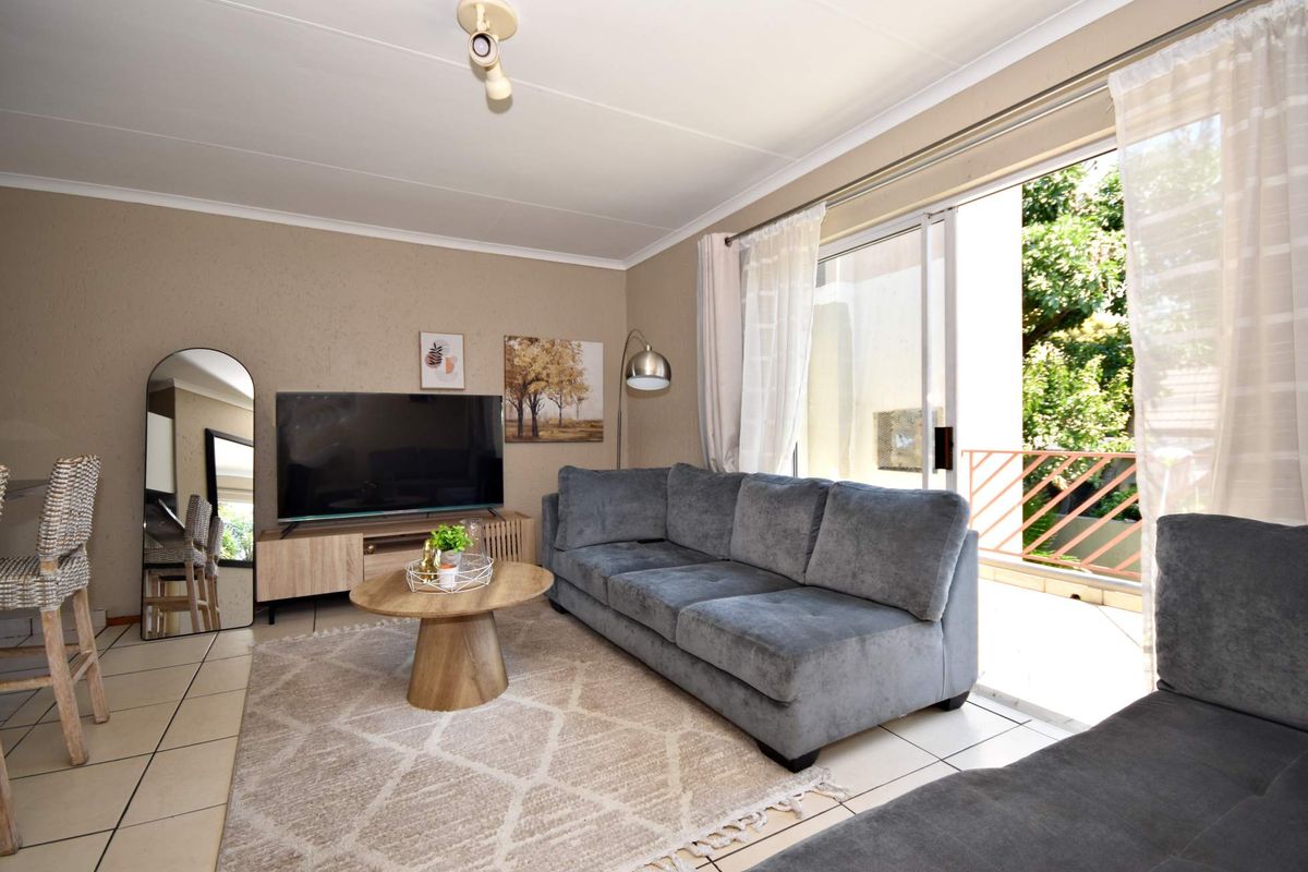 A well-maintained living room featuring tiled flooring and a large sliding glass door that provides access to an outdoor balcony area.